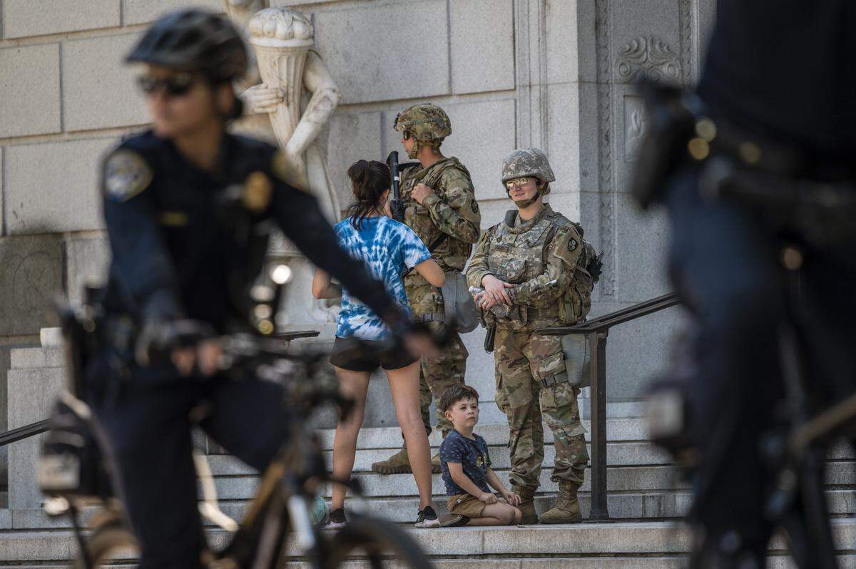 Elijah Ducey, 3, looks up while law enforcement officers and California National Guard patrol the State of California Stanley Mosk Library and Courts Building in Sacramento on Tuesday, June 2, 2020.