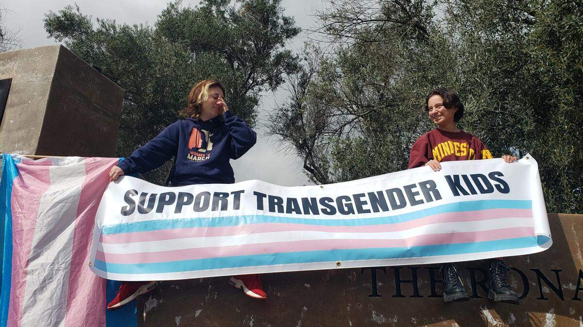 Ventura County residents Finn Samson and Sabrina Silva hold a sign that reads “Support Transgender Kids” next to a transgender pride flag at a protest against Florida Gov. Ron DeSantis outside the Ronald Reagan Presidential Library & Museum in Simi Valley on March 5.