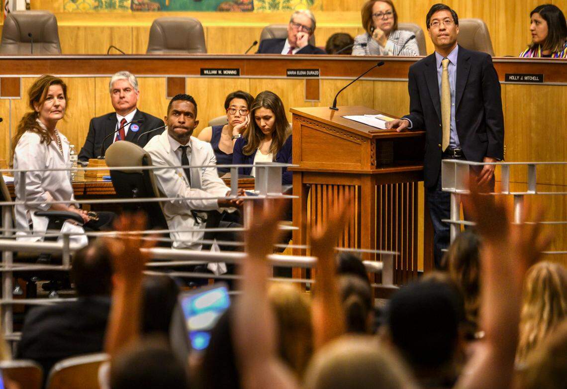 State Sen. Richard Pan listens to people speak against his Senate Bill 276, while protesters wave their hands to support the opposition, in 2019 at a Senate heath committee hearing. The bill eliminated personal belief exemptions to vaccination requirements for school attendance.