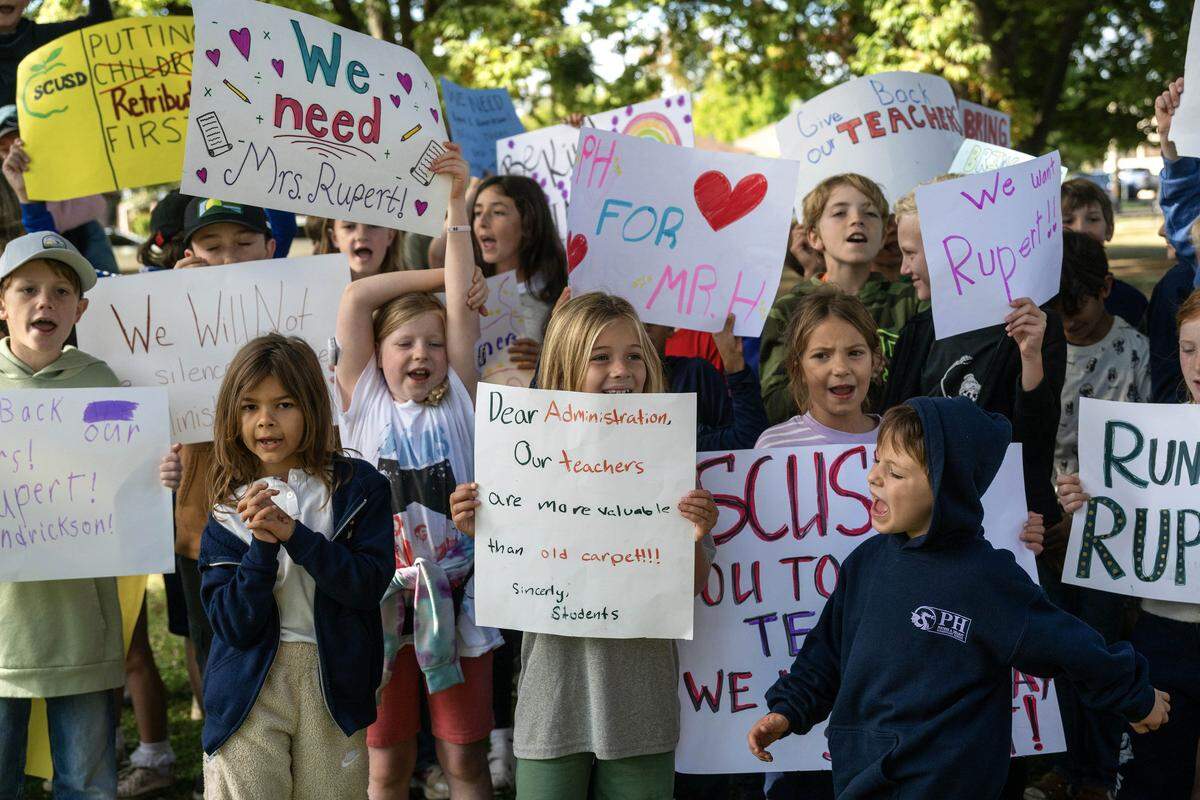 Students from Phoebe Hearst Elementary hold handmade signs during a walkout at East Portal Park in Sacramento on Monday, protesting the removal of sixth-grade teachers Jeanine Rupert and Mark Henrikson. At center, 7-year-old Emilia Lambruschini holds a sign reading, “Our teachers are more valuable than old carpet,” a reference to Rupert’s reassignment.