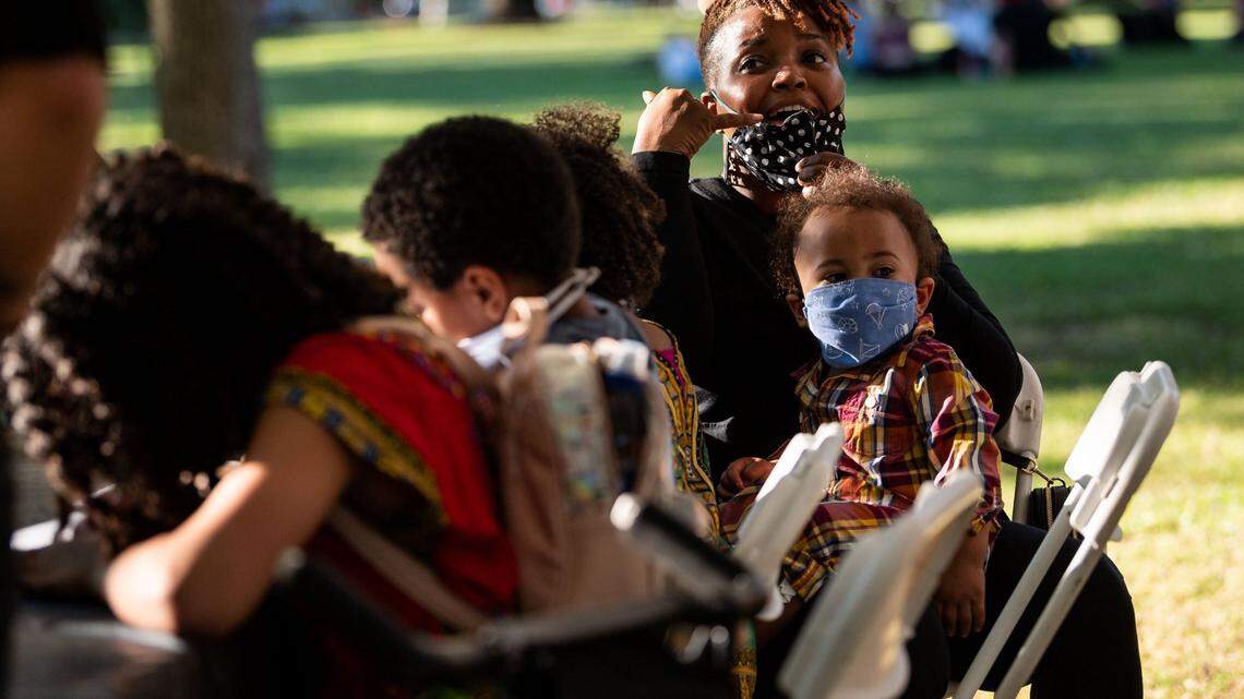 Katrina Simmons, who holds Ashley Simmons, 1, in her lap, socializes with family at Black Justice Sacramentos healing space event at Curtis Park on Tuesday, June 9, 2020, in Sacramento. The event was held for Black community members to heal, build solidarity and discuss future actions for the movement, according to a media advisory from the Black Justice Sacramento collective.