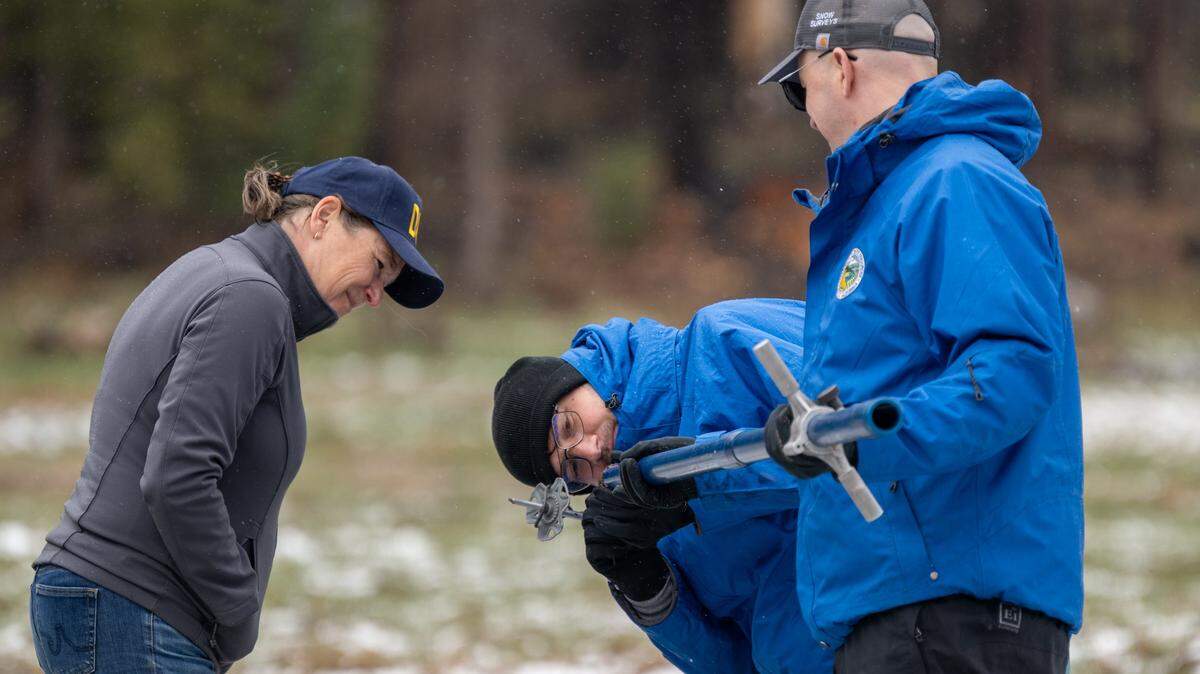 DWR Director Karla Nemeth watches Jim Shannon and Jacob Kollen measure the snow during the California Department of Water Resources snow survey at Phillips Station on Wednesday, April 1, 2026. They recored a measurement of zero inches of snow and the second lowest since 2015 during snow survey at the Phillips Station in the Sierra Nevada.
