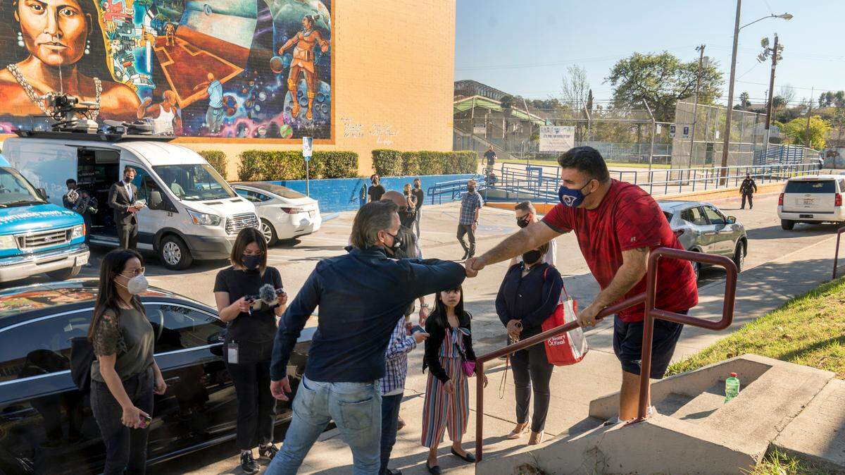 In February 2021, California Gov. Gavin Newsom, front left, greets resident Israel Ortiz after Newsom visited a Los Angeles mobile vaccination site while campaigning in Latino neighborhoods.