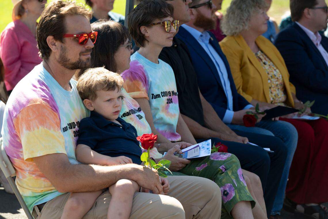 Lead artist Wesley Horn sits with his son Max as one of the guest speakers as the Davis Cemetery District unveils their COVID-19 Memorial to the public on Sunday.