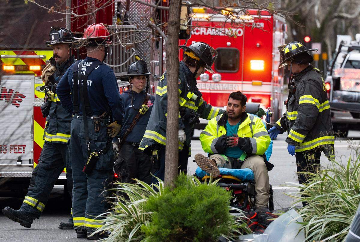 The first rescued construction worker is examined by Sacramento firefighters after being lowered from the facade of a building at 15th and Q streets on Wednesday.