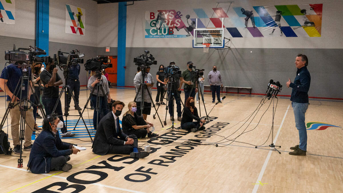 California Gov. Gavin Newsom, right, takes questions from the media after a visit to Ramona Gardens Recreation Center in Los Angeles to discuss the state’s efforts to vaccinate hard-to-reach and disproportionately impacted communities, Sunday, Feb. 21, 2021. California’s new system of delivering and scheduling coronavirus vaccines is being rolled out in select counties. It’s the first step in Newsom’s plan to smooth out what has been a disjointed vaccine rollout hampered by limited national supply.