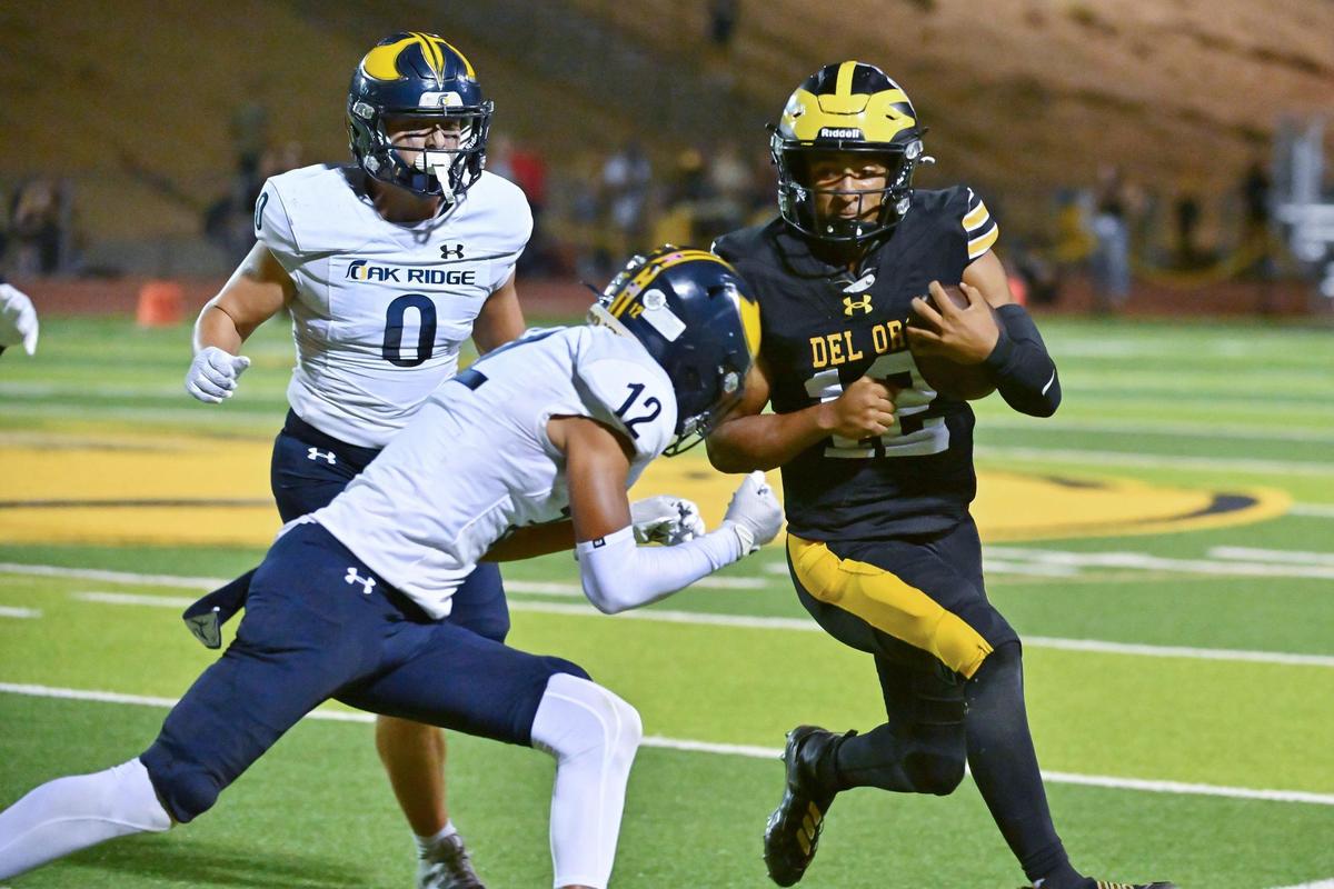 The Del Oro Golden Eagles’ Caden Pinnick (12) runs a quarterback keeper before being pushed out of bounds by the Oak Ridge Trojans’ Kevin Arnal (12) on Friday in Loomis.