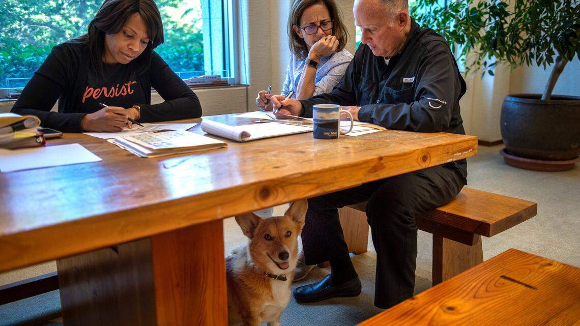 Gov. Jerry Brown, right, reviews legislation in his office  with First Lady Anne Gust Brown,  and Camille Wagner, legislative secretary. The Browns’ dog, Colusa, stands watch underneath the table at the California Capitol in Sacramento on Sept. 30, 2018. This was Brown’s last day signing bills while in office.