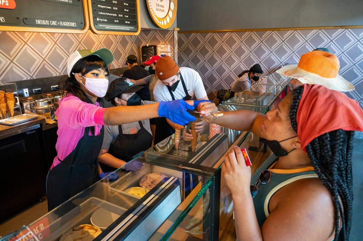 Salt & Straw’s Jackie Nelson hands a sample to midtown resident Georgia Russell at the opening day of the shop on R Street in midtown Sacramento on Friday, Sept. 2, 2022. Russell was considering several of the store’s zany flavors –&nbsp;including strawberry balsamic, pear and bleu cheese, or spiced goat cheese pumpkin pie – while waiting in line.
