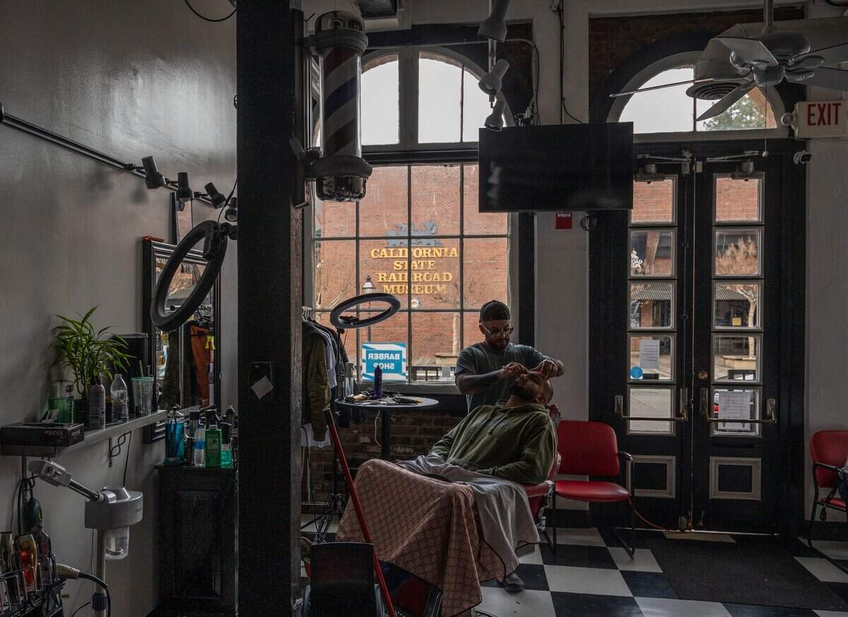 Alfonso Rivera of Sacramento Barbering Company cuts the hair of his client Chris Dutt of Sacramento Thursday, Dec. 16, 2021 in Old Sacramento, which has been without power since a SMUD substation fire on Tuesday. “I was cutting hair when the power went out,” said Rivera who witnessed the large cloud of smoke that lifted from the fire at 6th and H streets. Rivera is using a small gas generator to charge his cordless hair clippers and to run other small electronics.