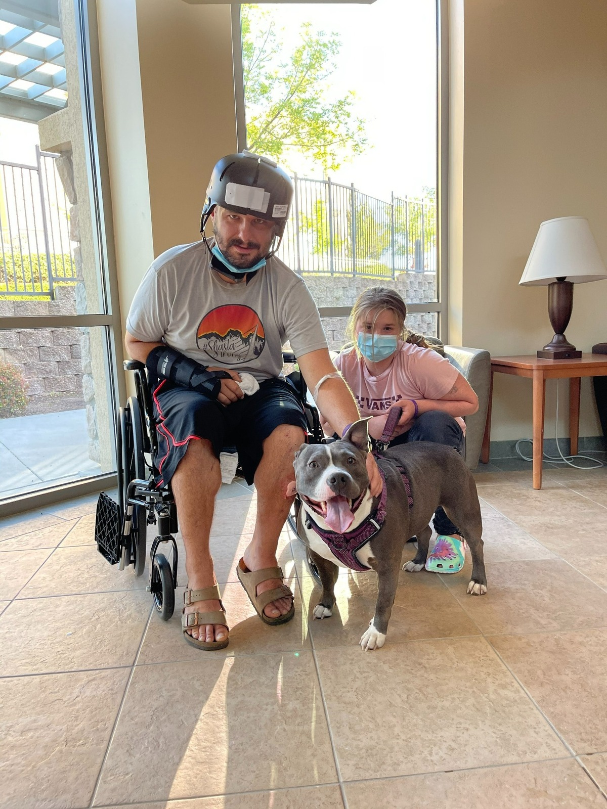 Travis Barber, 35, is visited by his pit bull Cookie and his stepdaughter Kayleann while rehabilitating from brain injuries in an April 2021 shooting in Lakehead, California.