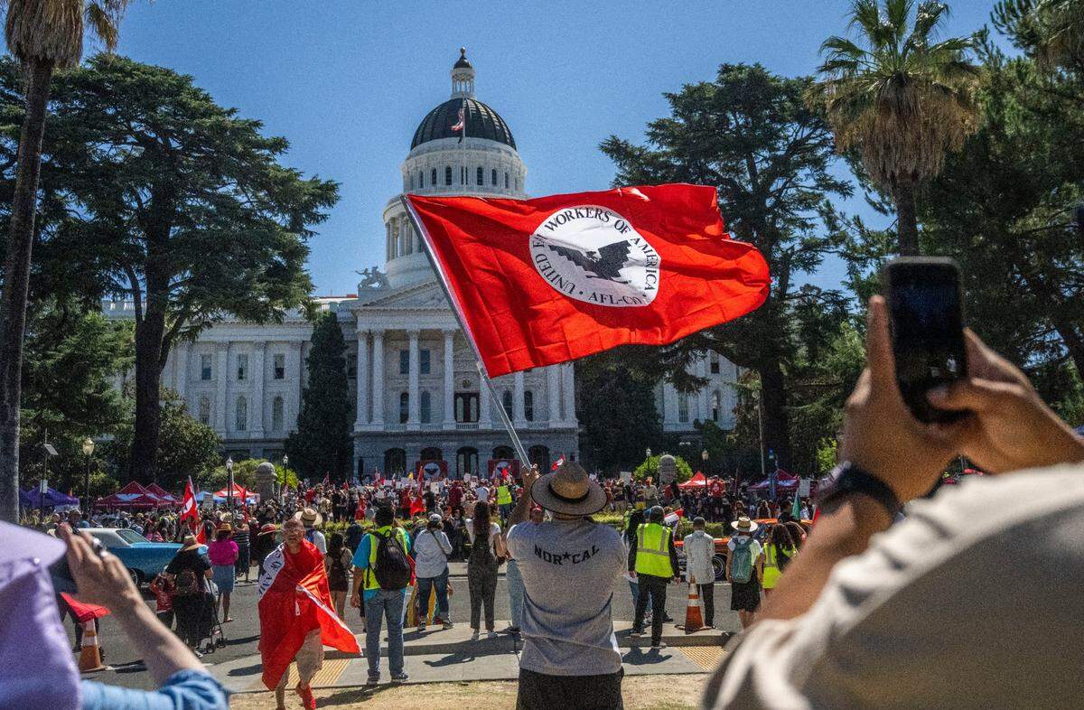 Joe Aguilar of Sacramento waves a United Farm Workers flag in front of the state Capitol in Sacramento after the union finished a 24-day march on Aug. 26 to call on Gov. Gavin Newsom to sign a bill that would give farmworkers the ability to vote from home to unionize.