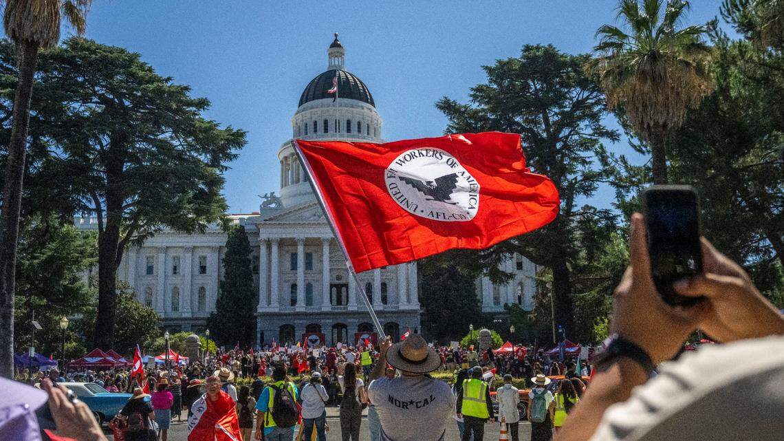 Joe Aguilar of Sacramento waves a United Farm Workers flag in front of the state Capitol in Sacramento last Aug. 26. The union had just finished a 24-day march to call on Gov. Gavin Newsom to sign a bill that would give farmworkers the ability to vote from home to unionize.