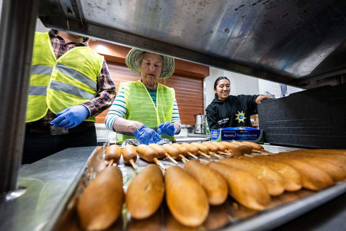 Anne Horton, a volunteer with the Brown Bag Lunch program at the Cathedral of the Blessed Sacrament, helps pack corndogs on Thursday.