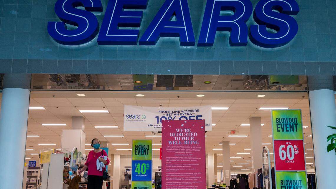A masked woman and child walk out after shopping at a blowout sale at Sears in Arden Fair mall in Sacramento on Monday, Feb. 1, 2021.