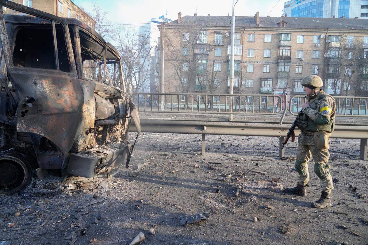 A Ukrainian soldier walks past debris of a burning military truck, on a street in Kyiv, Ukraine, Saturday, Feb. 26, 2022. (AP Photo/Efrem Lukatsky)