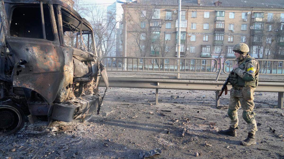 A Ukrainian soldier walks past debris of a burning military truck, on a street in Kyiv, Ukraine, Feb. 26. (AP Photo/Efrem Lukatsky)
