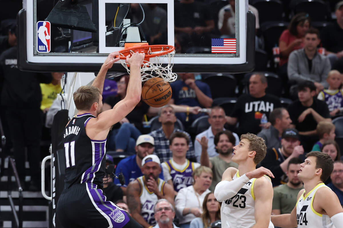 Sacramento Kings center Domantas Sabonis (11) dunks the ball against Utah Jazz forward Lauri Markkanen (23) and center Walker Kessler (24) during the first quarter of a preseason game Tuesday at Delta Center in Salt Lake City.