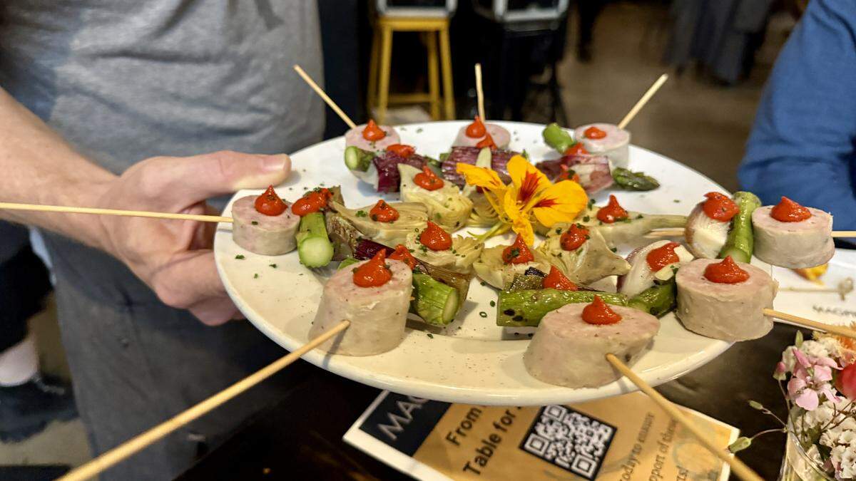 A server passes skewers with artichoke, charred green onion, asparagus and PT Ranch pork sausage as a bite at Magpie Cafe’s in Sacramento, CA on Wed., April 1. The farm-to-fork restaurant celebrated its 21st anniversary with an event serving free food to locals and industry folk.