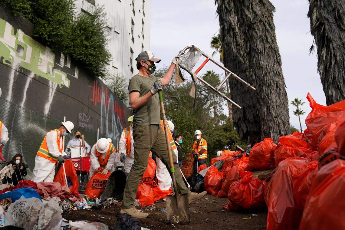 California Gov. Gavin Newsom helps clean a homeless encampment alongside a San Diego freeway in January. Newsom is calling for $65 million to fund his CARE Court plan, which would create mental health courts to order treatment for people with severe untreated mental illness.