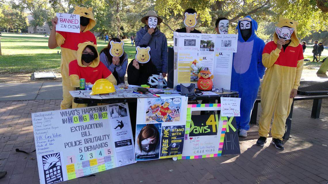 The “Davis4HK” student group members pose at their counter at UC Davis with posters, infographics and local protest icon “Lin Pig” to talk to fellow students about the Hong Kong protests on Oct. 30, 2019.