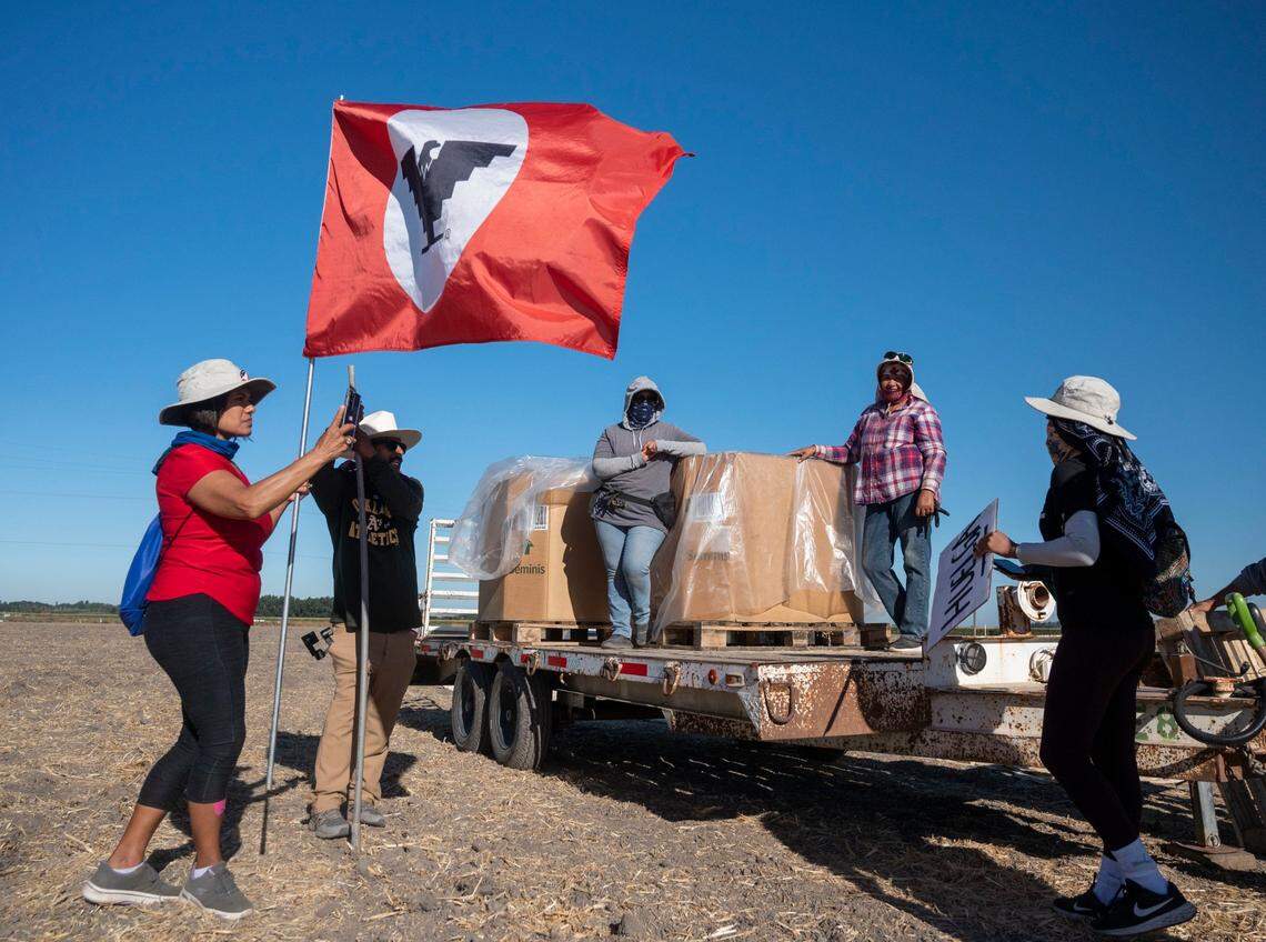 United Farm Workers Union members Carmen Hernandez, left, of Turlock, Olegario Filoso, of the Bay Area, and Flor Martinez Zaragoza, of San Jose, right, speak to farmworkers Maria Soto of Clarksburg and Amelia Sagun of Sacramento during a break in their march in Walnut Grove on Wednesday.
