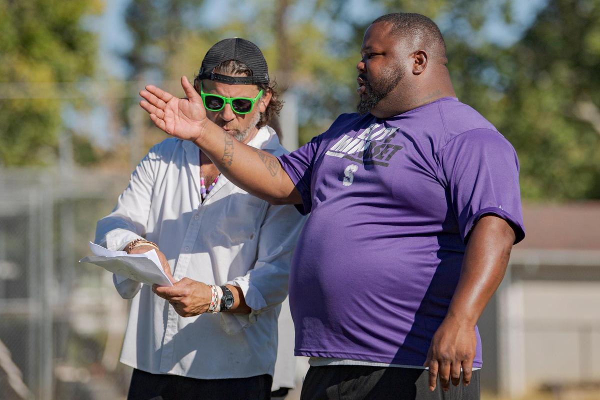 Sacramento High School football coaches Kimbbie Dayton, right, and Paul Peterson go over plays at practice on campus in July.