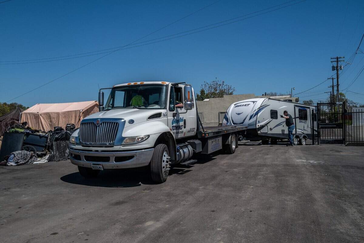 Workers deliver a city-owned travel trailer to Camp Resolution, a self-governing homeless encampment in North Sacramento, on Monday.