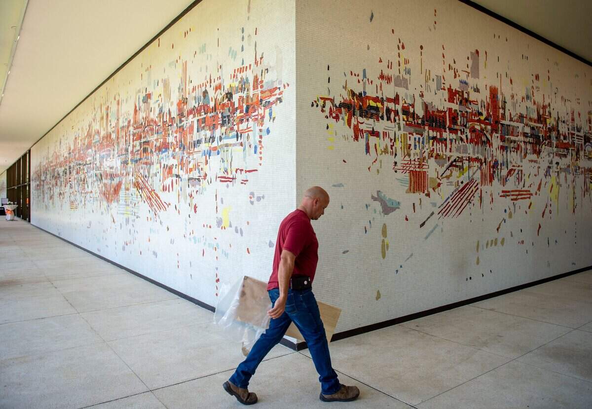 A SMUD employee walks past “Water City,” an abstract mosaic mural by Wayne Thiebaud, at the historic SMUD headquarters building in Sacramento in August 2019, after the mural was cleaned and restored as part of the renovation of the iconic building.