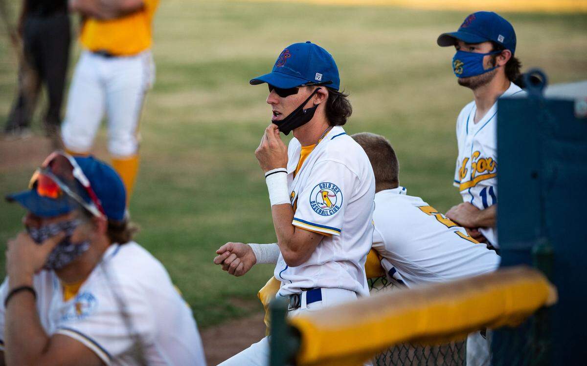 Yuba-Sutter Gold Sox’s Jonathan Kimball watches from the dugout with fellow mask-wearing teammates as they take on the Lincoln Potters of Placer County on Thursday, July 9, 2020, at Colusa Casino Stadium in Marysville. The team has found a way to have a season by conducting temperature checks upon arrival, requiring facial coverings for entry and limiting seating to 100 fans per game while spacing seating to maintain social distancing.