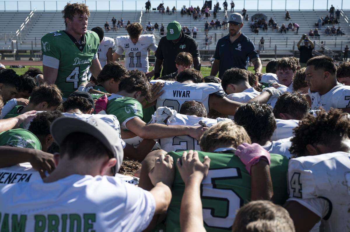Members of the Dixon High School football team pray alongside members of the Casa Roble High School football team after a game in Dixon between the two teams on Saturday, Oct. 18, 2025. The game followed the death of one of Dixon’s junior varsity football players.