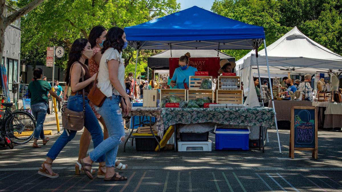 New vendors Sarah Schwemberger and Krysten Vinson of Mountain Ranch work their farm booth, Hideaway Acres, for the first time, Saturday, April 17, 2021, at the expanded Midtown Farmers Market in Sacramento. Coinciding with a surge in patronage from shoppers eager to leave their homes and enjoy the weather after months stuck indoors, market organizers decided to add shopping space on K Street from 19th and 21st streets in addition to the usual market area along 20th Street.