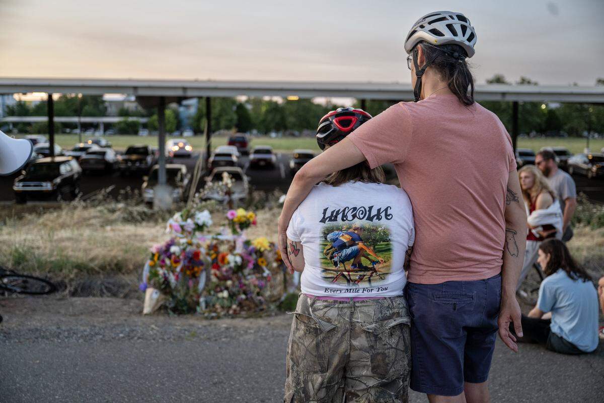 Keith Sabini and Rucha Powers, whose son Lincoln Sabini was killed while bicycling at UC Davis, pay their respects at a ghost bike near the site of his fatal crash during a memorial ride on Wednesday.