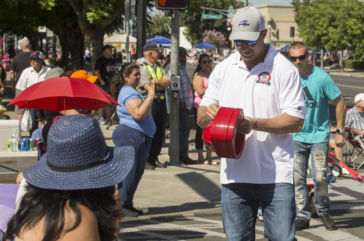 Assemblymember Heath Flora walks the Modesto Fourth of July parade route handing out fire hats in 2018.