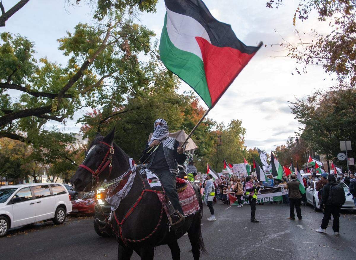 A demonstrator carrying the Palestinian flag rides a horse named Midnight in front of a protest march in support of Palestine near the Memorial Auditorium in downtown Sacramento on Saturday. The protesters were calling for a cease-fire in the Israel-Hamas war.