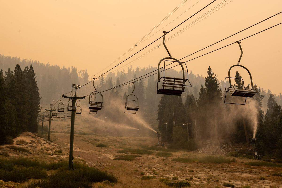 Snow-making machines spray water on the slopes of Heavenly Mountain Resort on the California-Nevada border near South Lake Tahoe while the Caldor Fire burns in 2021. People forced to flee the Lake Tahoe Basin during a wildfire emergency could face a life-threatening, hours-long, slog to safety, a new report reveals.