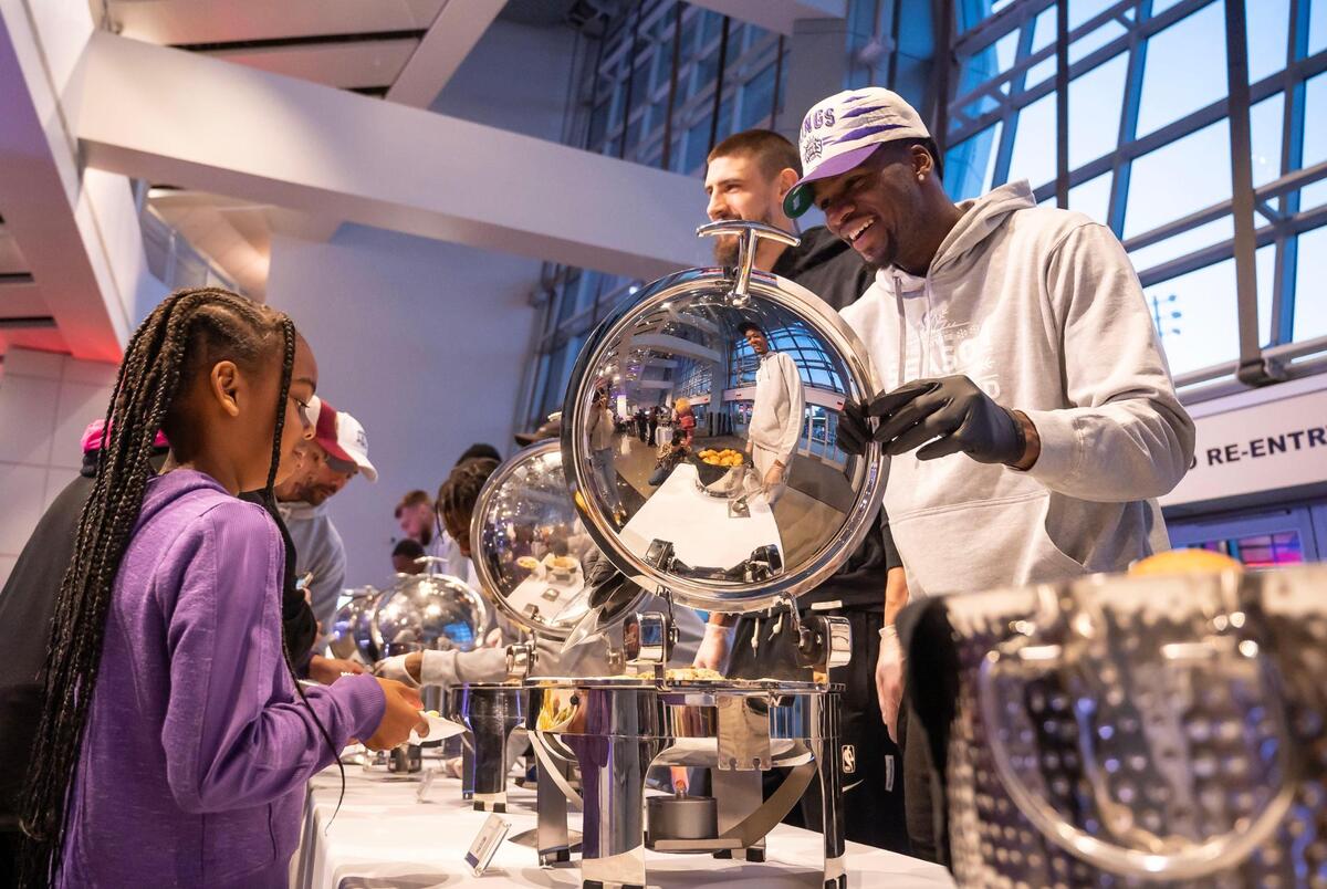 Sacramento Kings guard Terence Davis, right, serves children and other community members during the Sacramento Kings’ “Eat Like a King” event Wednesday.