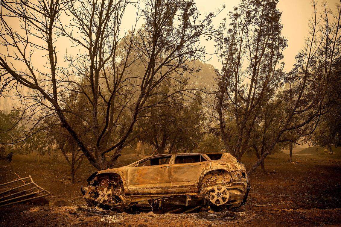 A scorched vehicle rests sits next to a driveway as the McKinney Fire burns in Klamath National Forest on Sunday.