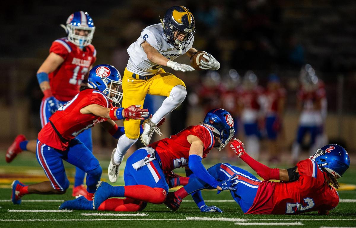 The Oak Ridge Trojans’ Jadon Anderson (6) leaps over Folsom Bulldogs defenders Cade Dutton (2) and Jasiah Banks (21) before being tripped by Daniel Chavez (10), left, in the second half of the CIF Sac-Joaquin Section Division I football championship game on Friday at Hughes Stadium.