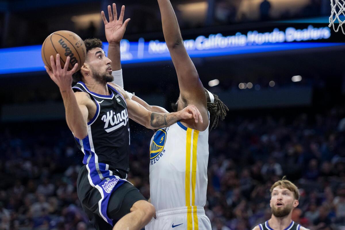 Sacramento Kings guard Chris Duarte (3) goes up for a layup over Golden State Warriors forward Kevon Looney (5) in the first half of the preseason NBA basketball game on Sunday at Golden 1 Center.