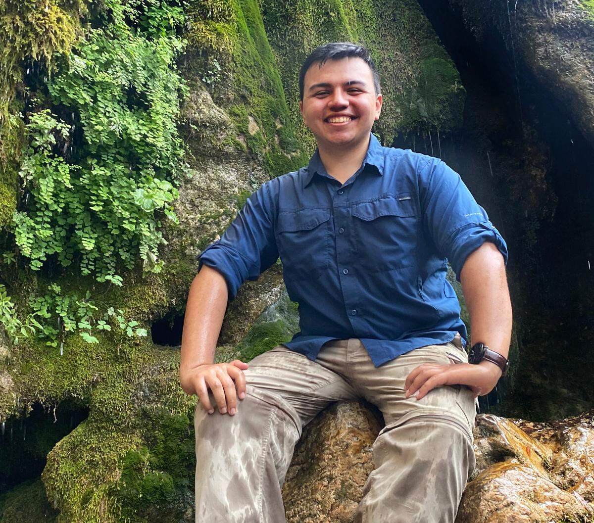 Amado Castillo sits amid the moss at Rose Valley Falls in the Los Padres National Forest during a Latino Conservation Week camping event in July 2021.