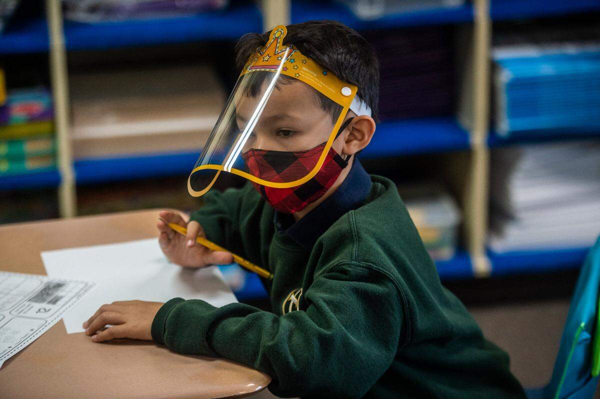First grader Mateo Galvez wears a face shield as he sits at his desk during the first day of in-person instruction at St. John Vianney School in Rancho Cordova on Monday, Sept. 14, 2020. Nineteen private schools in Sacramento County were granted waivers last week allowing in-person teaching during the coronavirus pandemic for K-6 students.