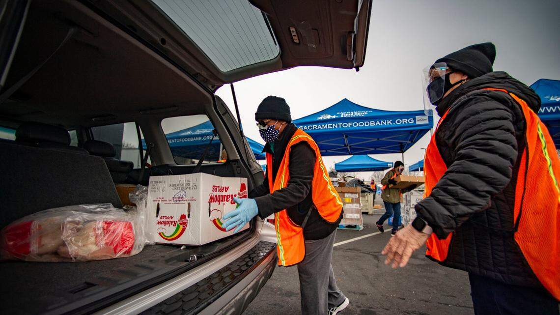 Volunteer Carolyn Hairston, of Elk Grove, loads boxes of food into cars that are waiting at Hiram Johnson High School on Friday, Jan. 8, 2021, to pick up food at one of the “touchless” food distribution sites run by the Sacramento Food Bank.