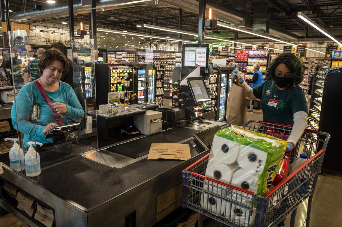 A customer at Raley’s pays for her groceries at check out at the newly opened store in South Land Park on Wednesday, April 15, 2020. Plastic shields have been installed at the checkout counters to help mitigate the spread of coronavirus.