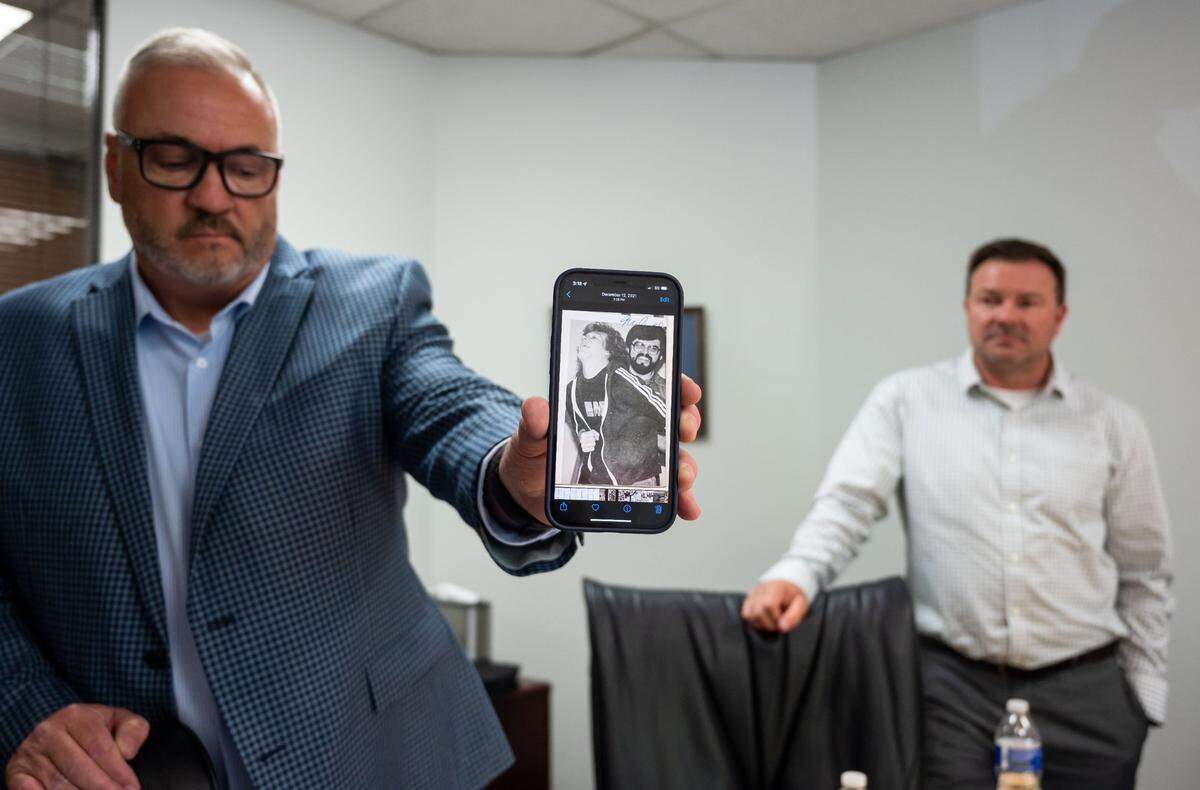 Scott Sorgea shows a copy of a yearbook photo on his phone showing former Capital Christian School coach and teacher Dave Arnold holding one of his former students. Sorgea said during that time, Arnold routinely tied him up, blindfolded, gagged and subjected him to psychological abuse, eventually gratifying himself sexually. Sorgea and his younger brother Darren Sorgea, right, spoke about the alleged abuse and coverup at the Sacramento private school. The two men are among a handful of former students taking legal action.