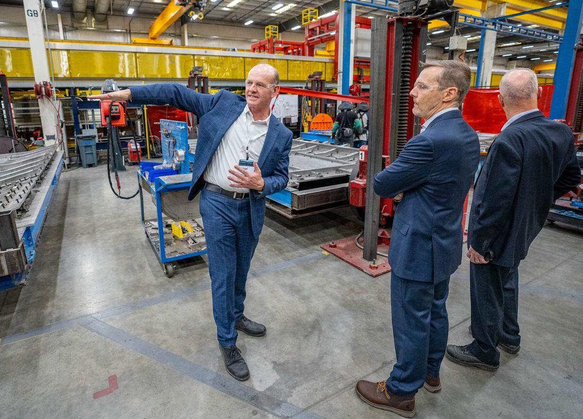 Michael Cahill, left, president of Siemens Mobility North America Rolling Stock, shows Amtrak President Roger Harris, middle, and other visitors around the Siemens Mobility manufacturing facility in Sacramento on Wednesday.