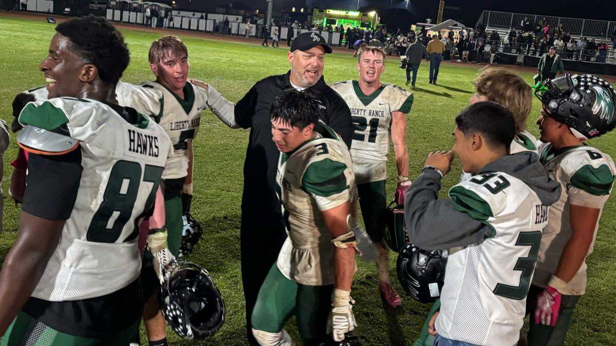 Liberty Ranch head coach Warren Schroeder, center, celebrates with his players after a 28-21 win over Bradshaw Christian on Friday. The victory keeps the Hawks undefeated and in control of the Sierra Valley Conference title race with two games remaining in the regular season.