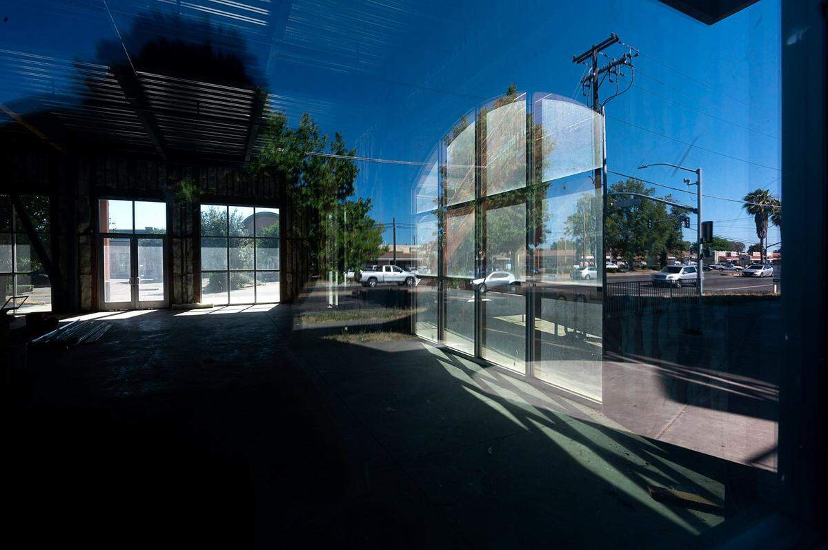 Cars are reflected in the windows of an abandoned building in a new shopping center on Stockton Boulevard and Riza Road on Thursday, May 28, 2020, in Sacramento’s Little Saigon business district that is struggling to survive economically during the coronavirus pandemic.