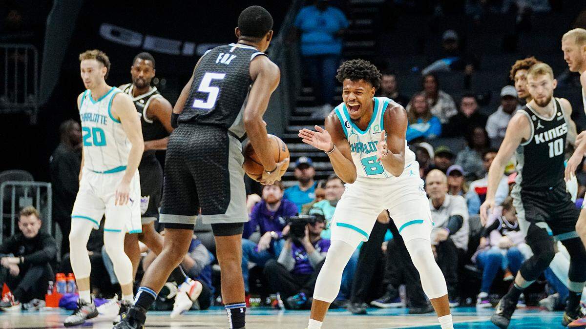 Charlotte Hornets guard Dennis Smith Jr. (8) celebrates a play as Sacramento Kings guard De’Aaron Fox (5) brings the ball upcourt during the first half of an NBA basketball game Monday, Oct. 31, 2022, in Charlotte, N.C. (AP Photo/Rusty Jones)