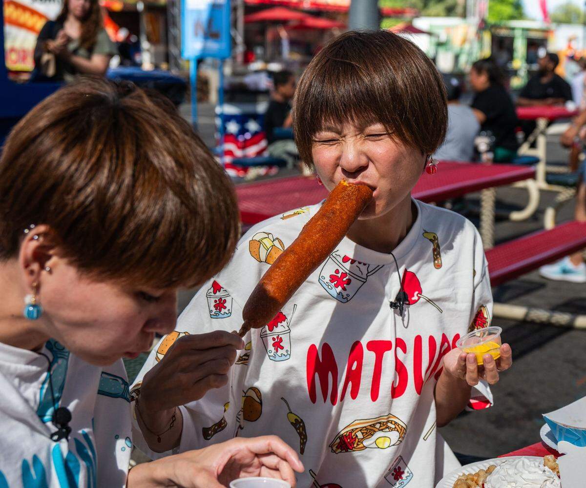 Ako Ono bites into a “monster corndog” from Milo’s at the California State Fair on Friday. Ono shares a YouTube channel with her twin sister Kako Ono, who are together known as the “hungry twins.”